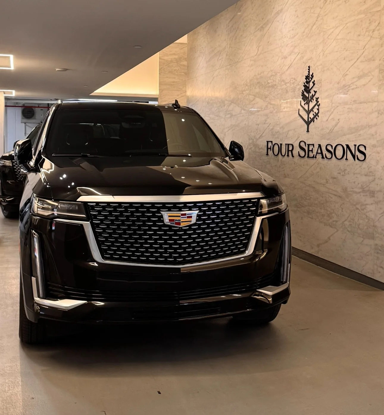 Black Cadillac Escalade beside the Four Seasons hotel sign.