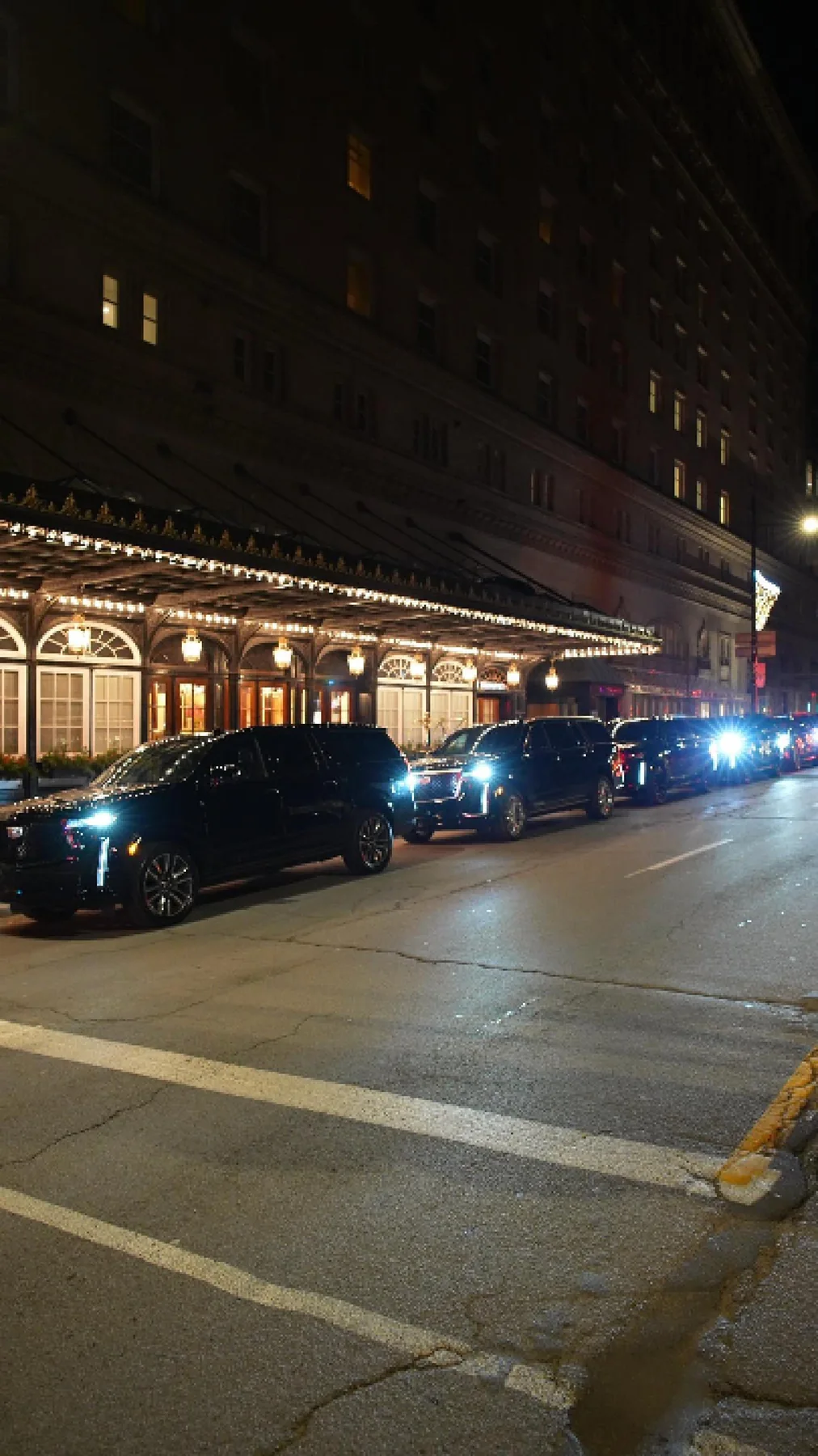 Black SUVs outside the illuminated Ritz-Carlton entrance at night.